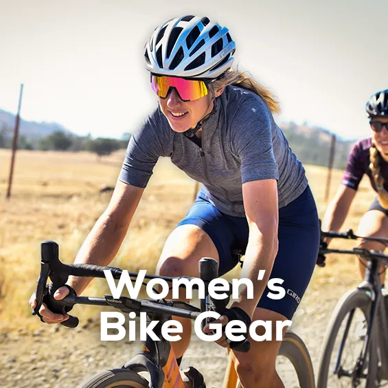 A woman riding a road bike wearing Giro cycling apparel including a Giro helmet, gloves, cycling jersey and shorts. Shop all women's bike gear from Sun & Ski Sports.