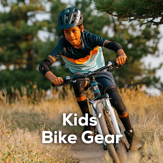 A younger boy riding a mountain bike wearing Pearl iZUMi bike gear. Shop all Kids' Bike gear from Sun & Ski Sports. 