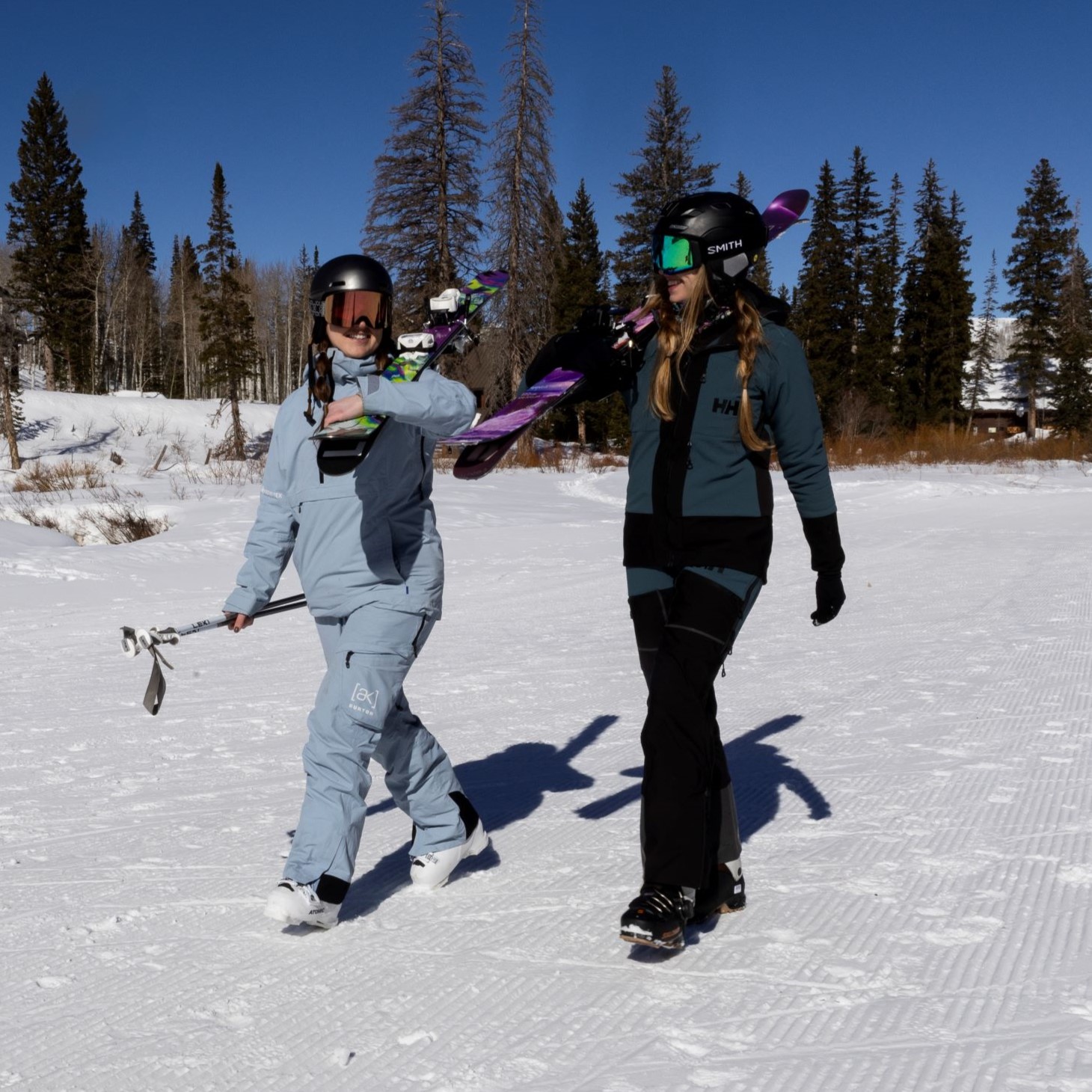 two women holding skis wearing their clean ski kit. 