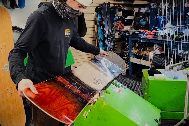 Sun & Ski Sports shop technician edging a snowboard in snowboard shop 