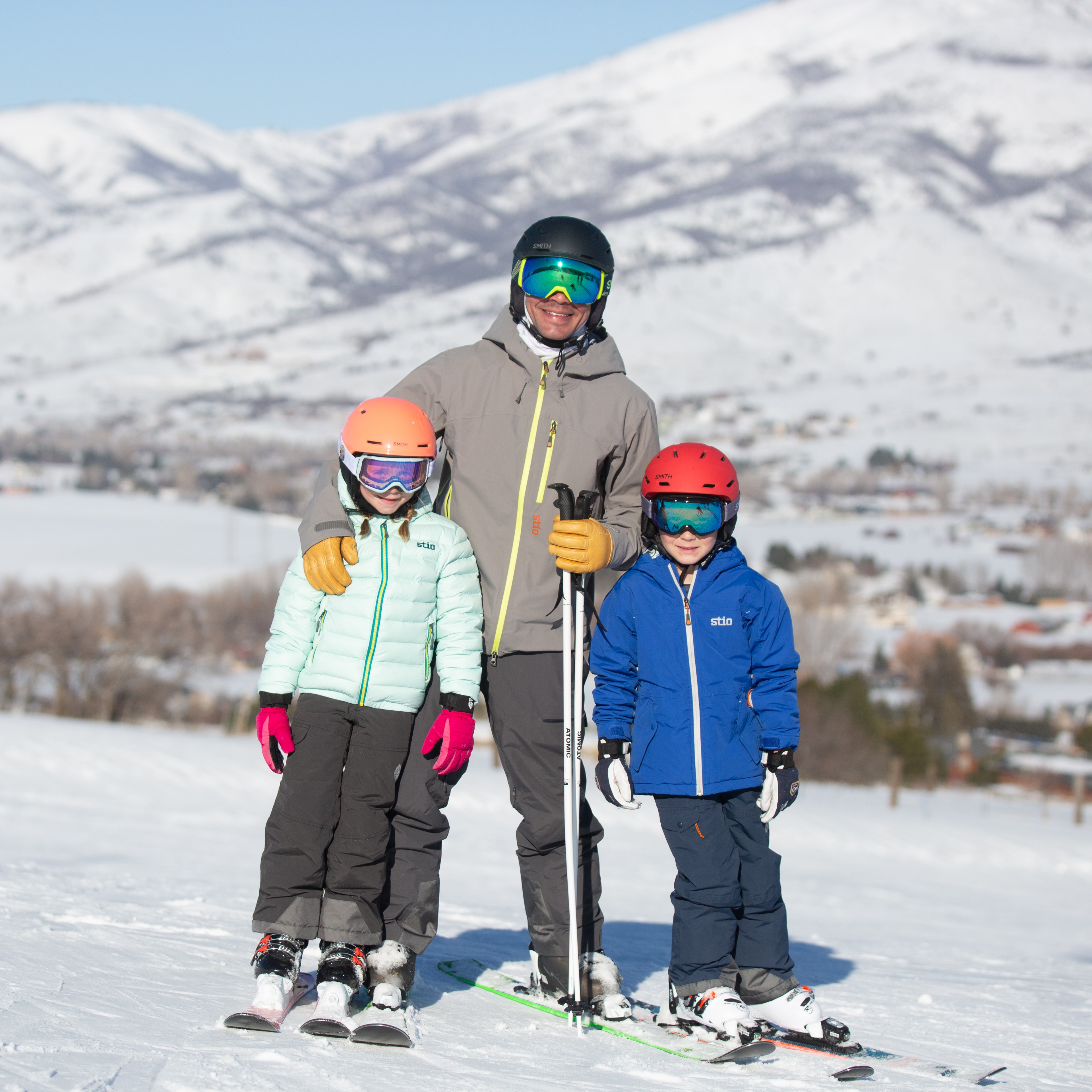 Two children skiing with parent making memories on the mountain.