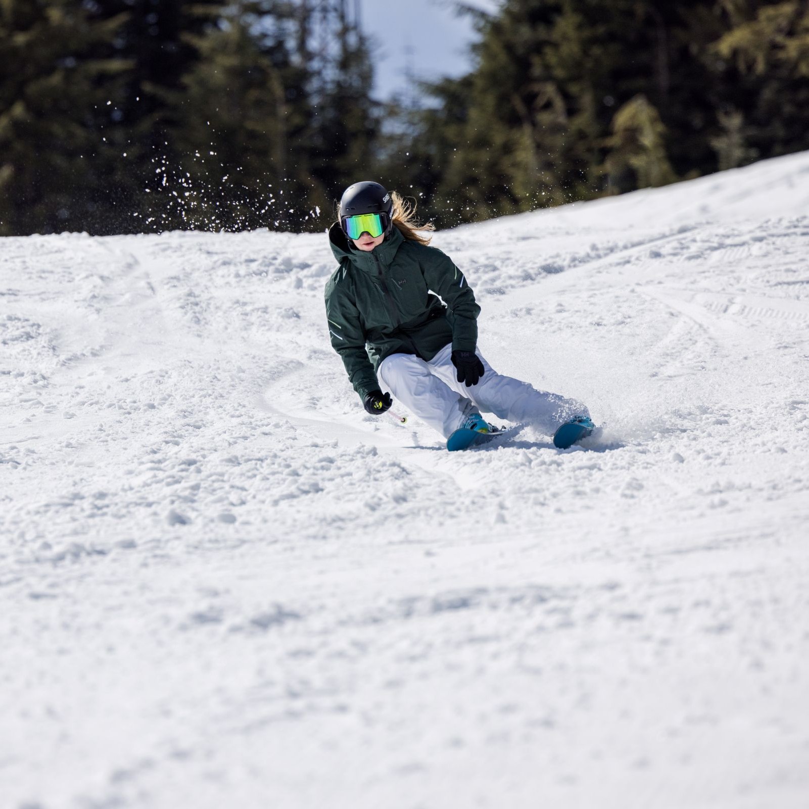 Woman skiing downhill on piste with ski poles.