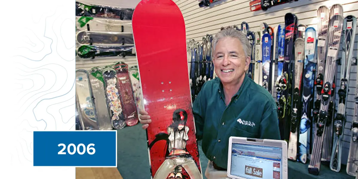 Barry Goldware showcasing snowboard equipment on display at a Sun and Ski Sports store.
