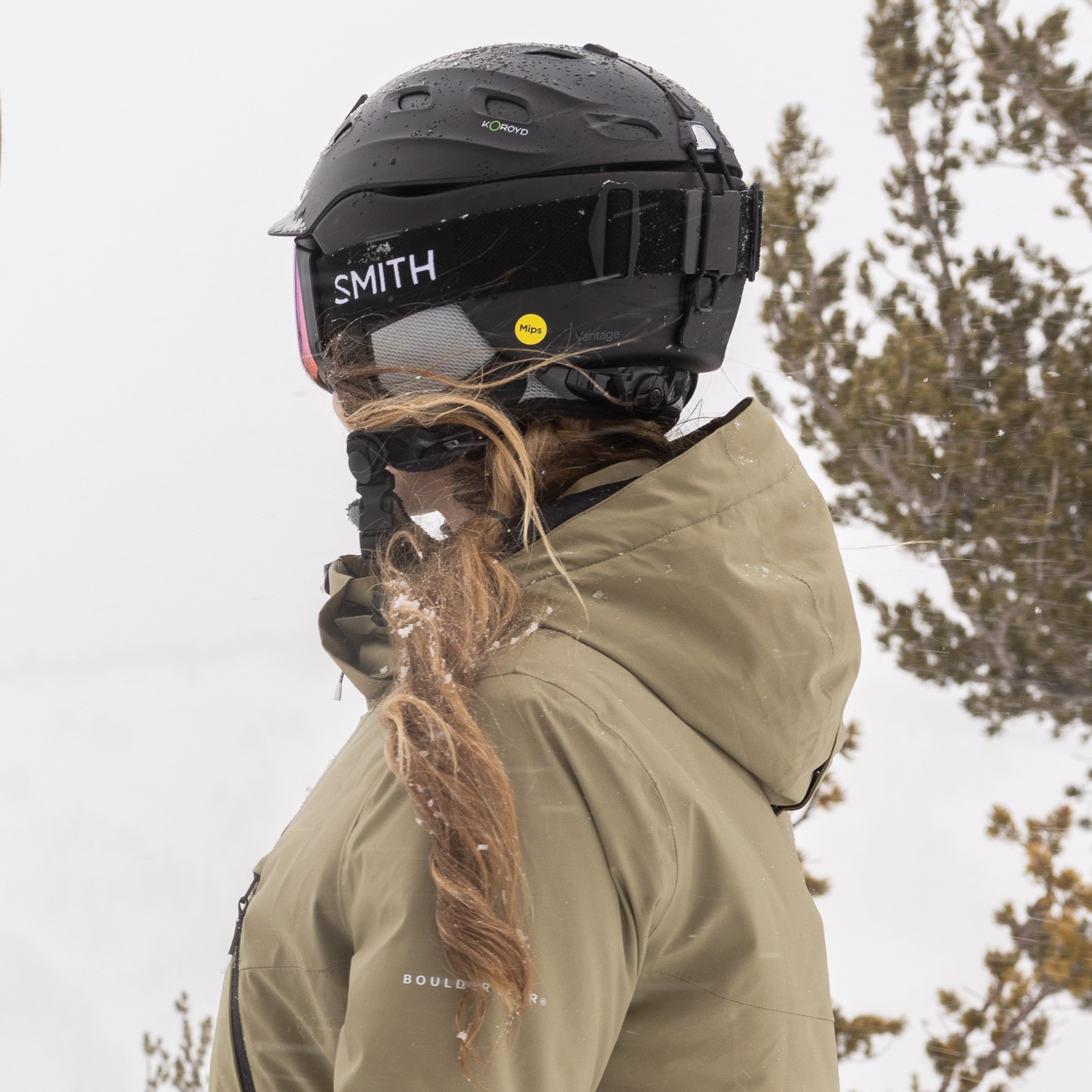 Woman looking over cliff at a scenic ski resort wearing smith ski helmet.  