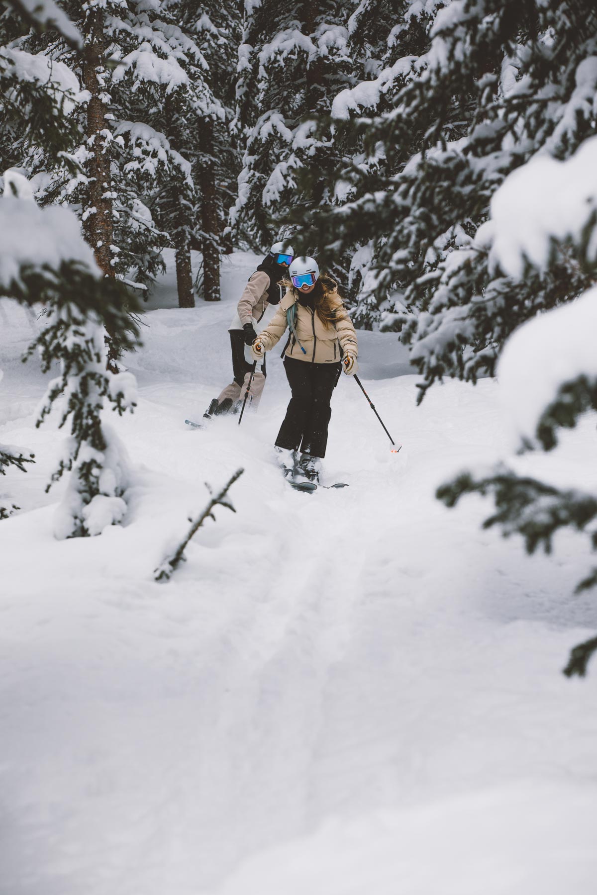 Two people skiing between trees