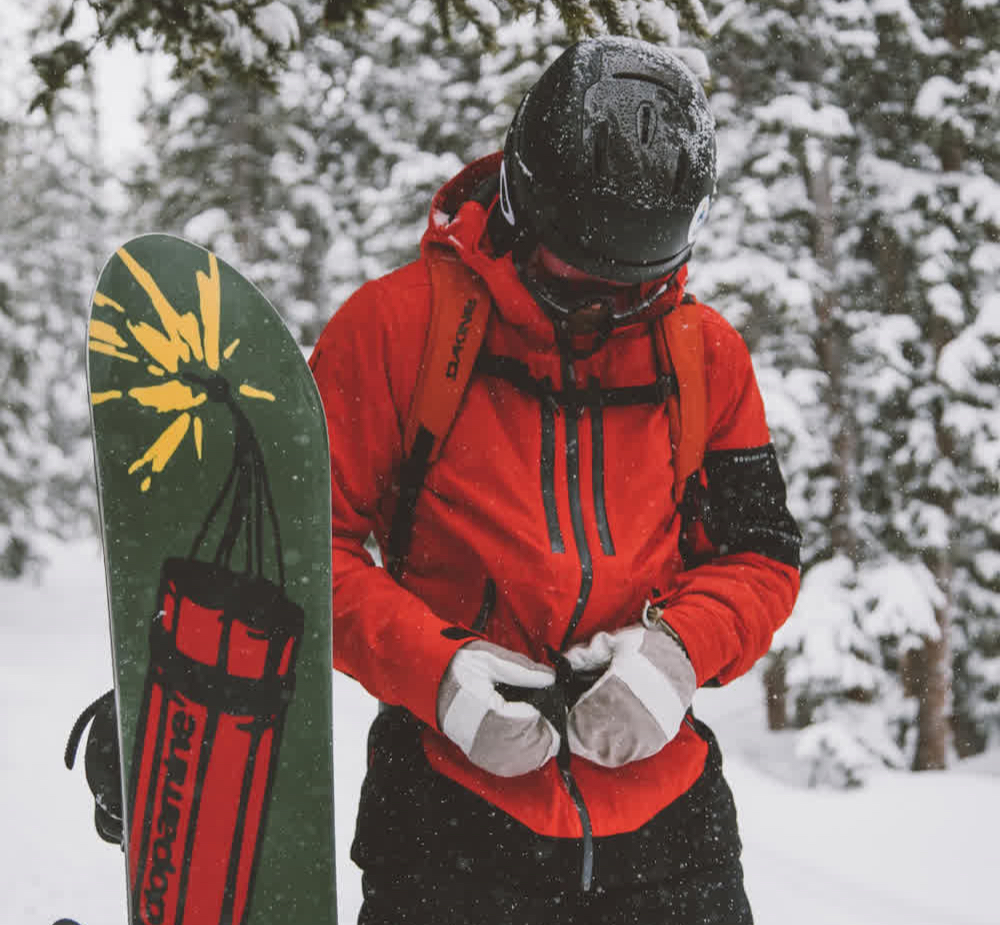 A man standing next to his snowboard.