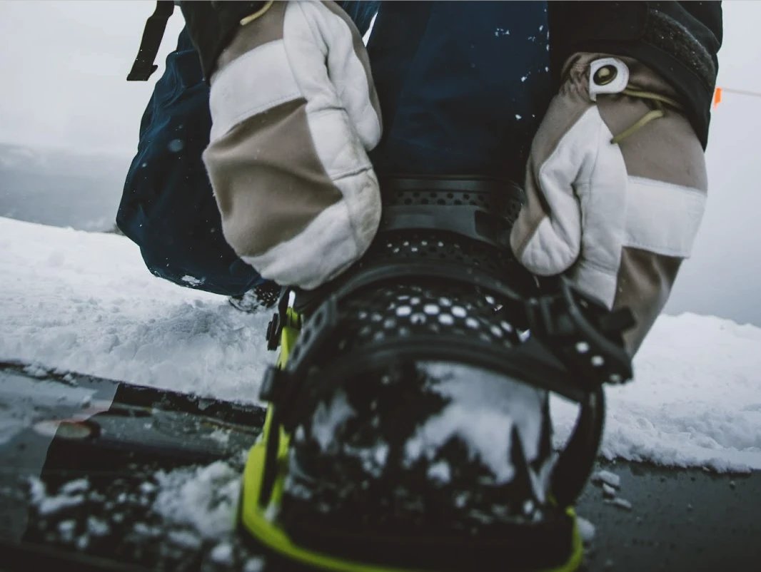 A snowboarder connecting their boots to their board with secure bindings.