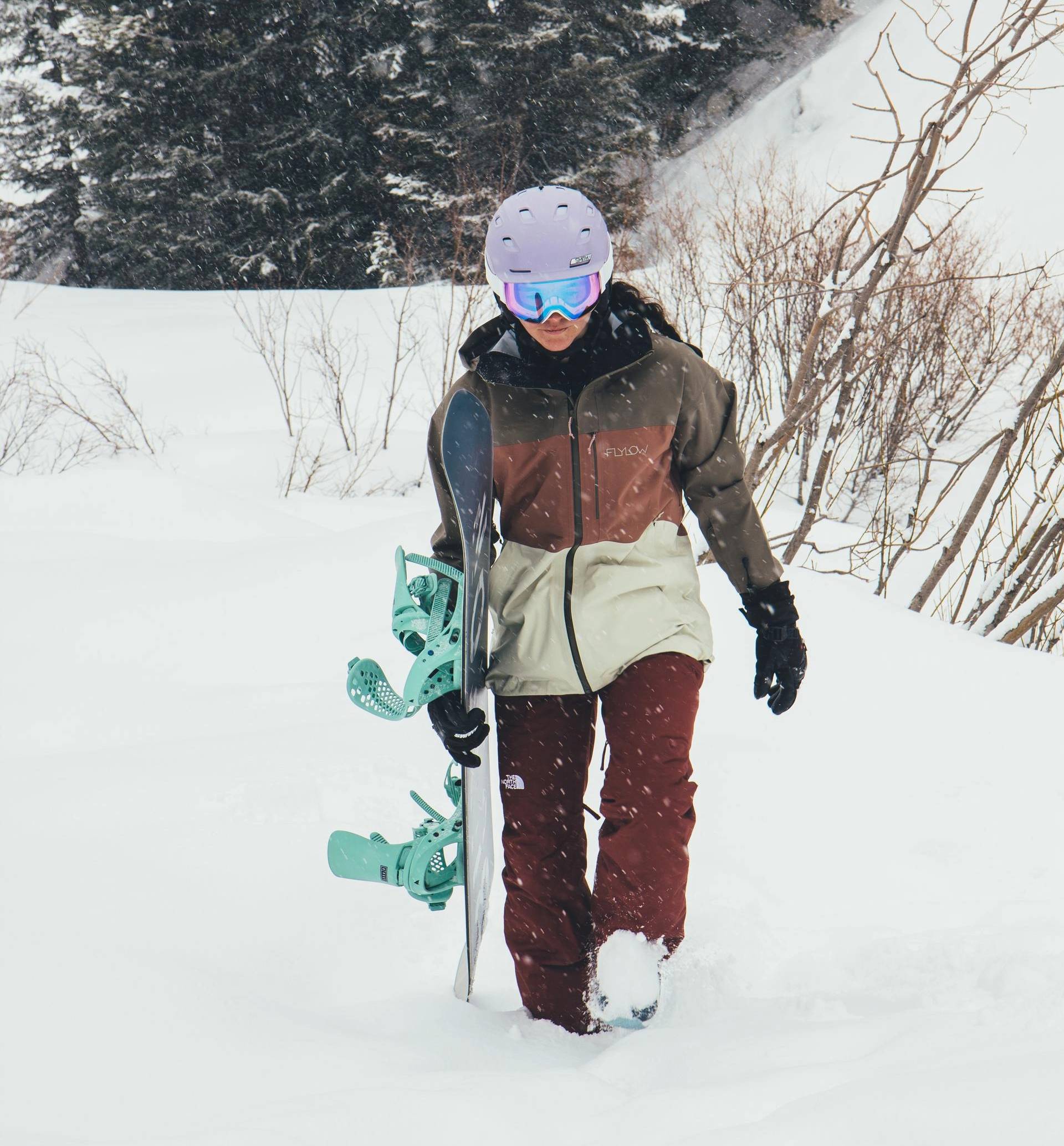 Rider walking through the snow while carrying snowboard