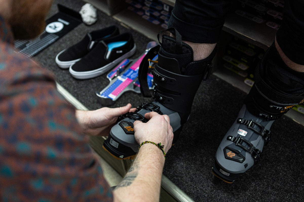 An Outdoor Expert helping a customer with their snowboarding boots