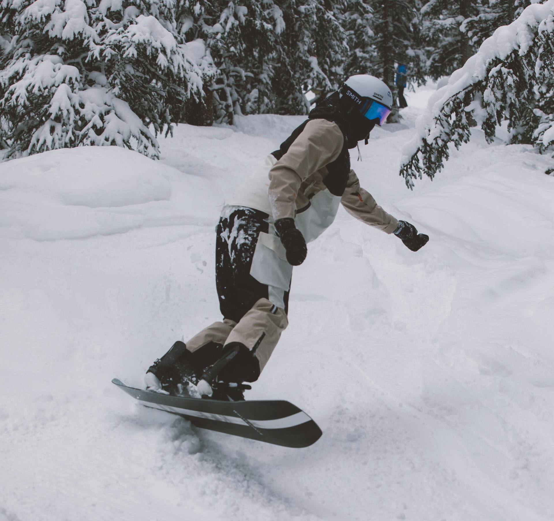Rider in action on a snowboard surrounded by snow and trees
