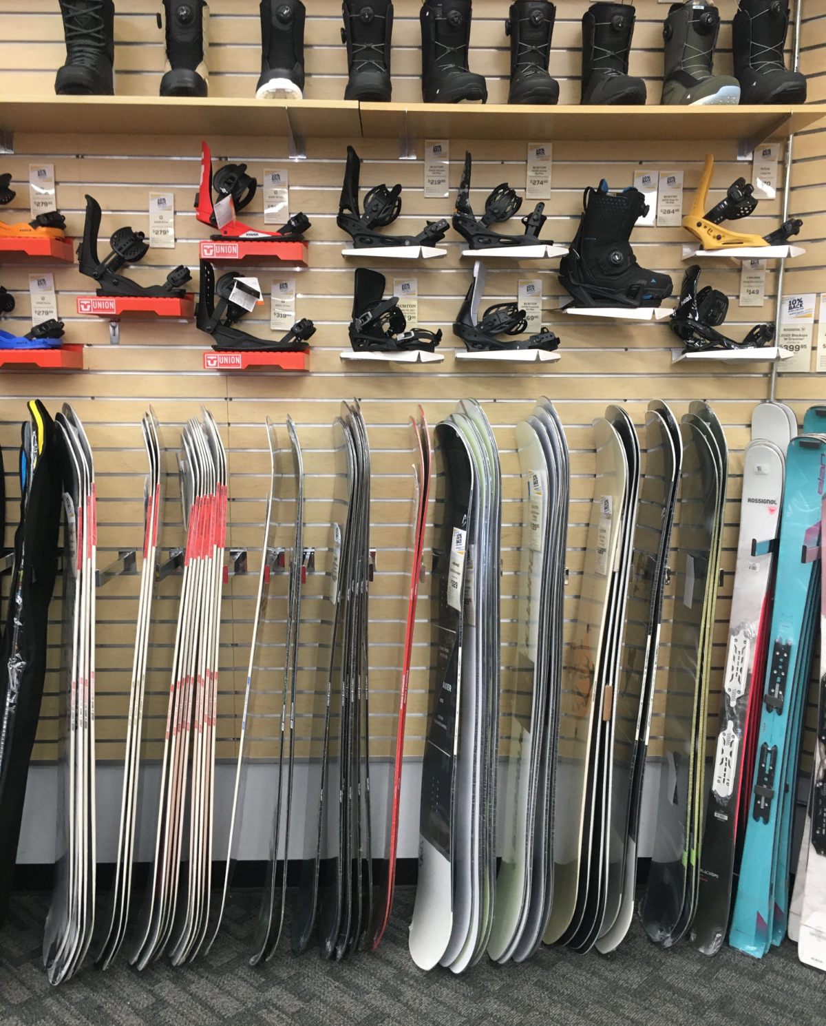 A wall display with snowboards, mountings, and boots