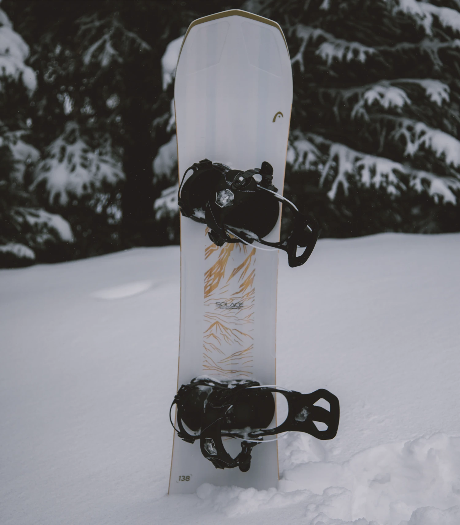 Alt: Snowboard with mounted bindings standing in fresh powder