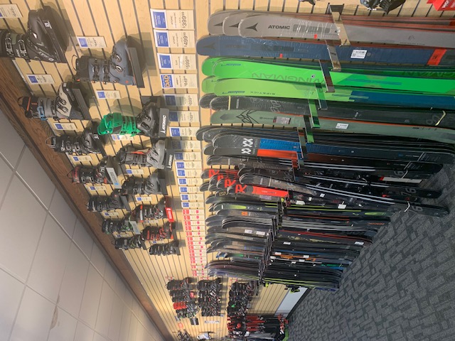 Racks showcasing available skis and ski boots at Sun & Ski Sports in Woburn