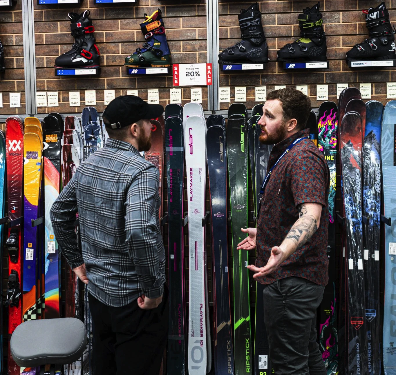 An Outdoor Expert at Sun & Ski Sports talking with a customer while viewing the skis on display